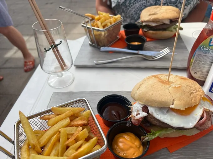 Hamburguesa con huevo y bacon y patatas fritas servidas en la terraza de Caravan Corner
